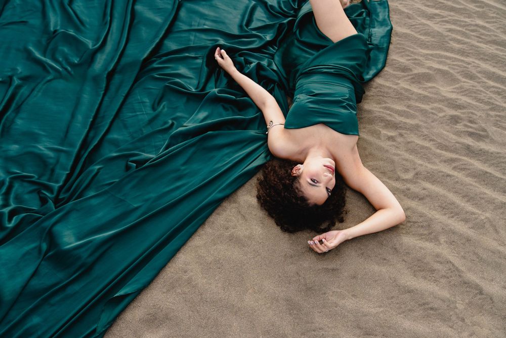 Dramatic fashion photo of a flowing teal dress on sandy beach.