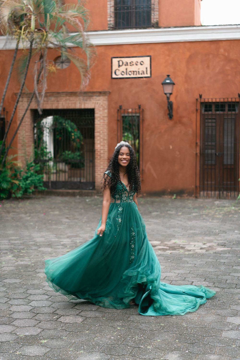 Elegant emerald green ballgown photographed against rustic colonial architecture.