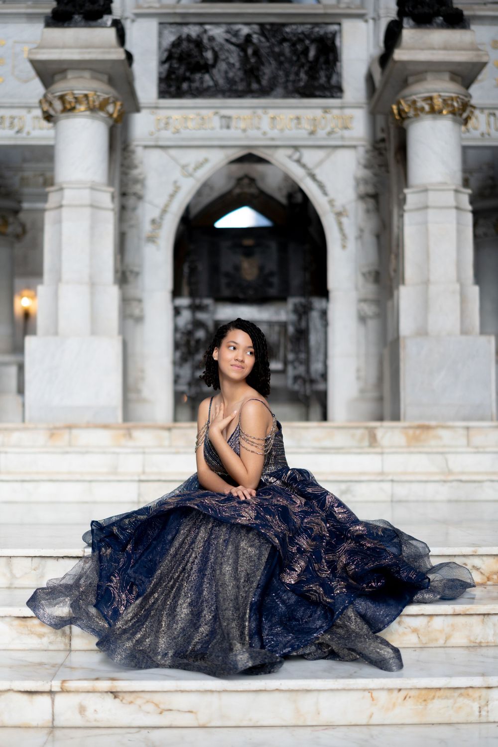 Elegant evening gown portrait session on ornate marble steps with classical architecture.