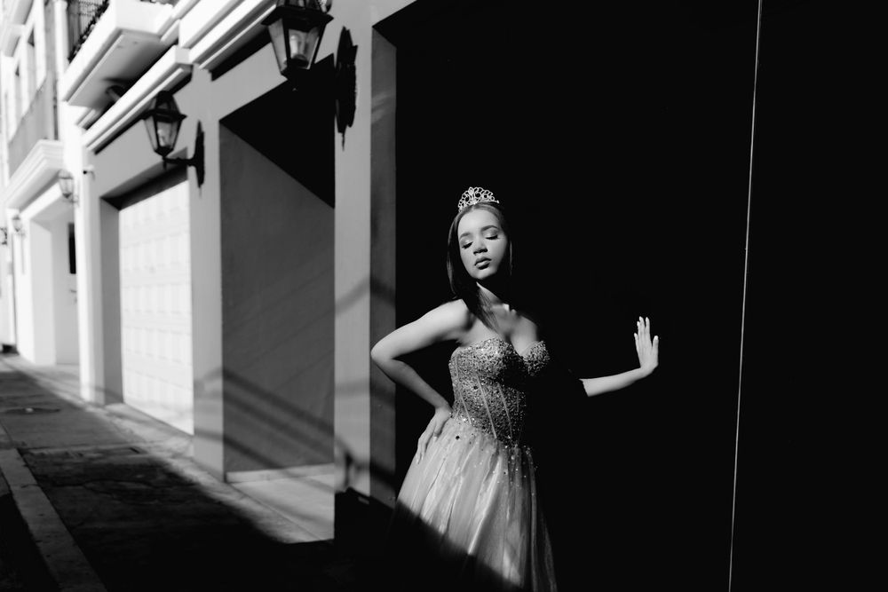 Black and white portrait of dancer in elegant dress between architectural columns.