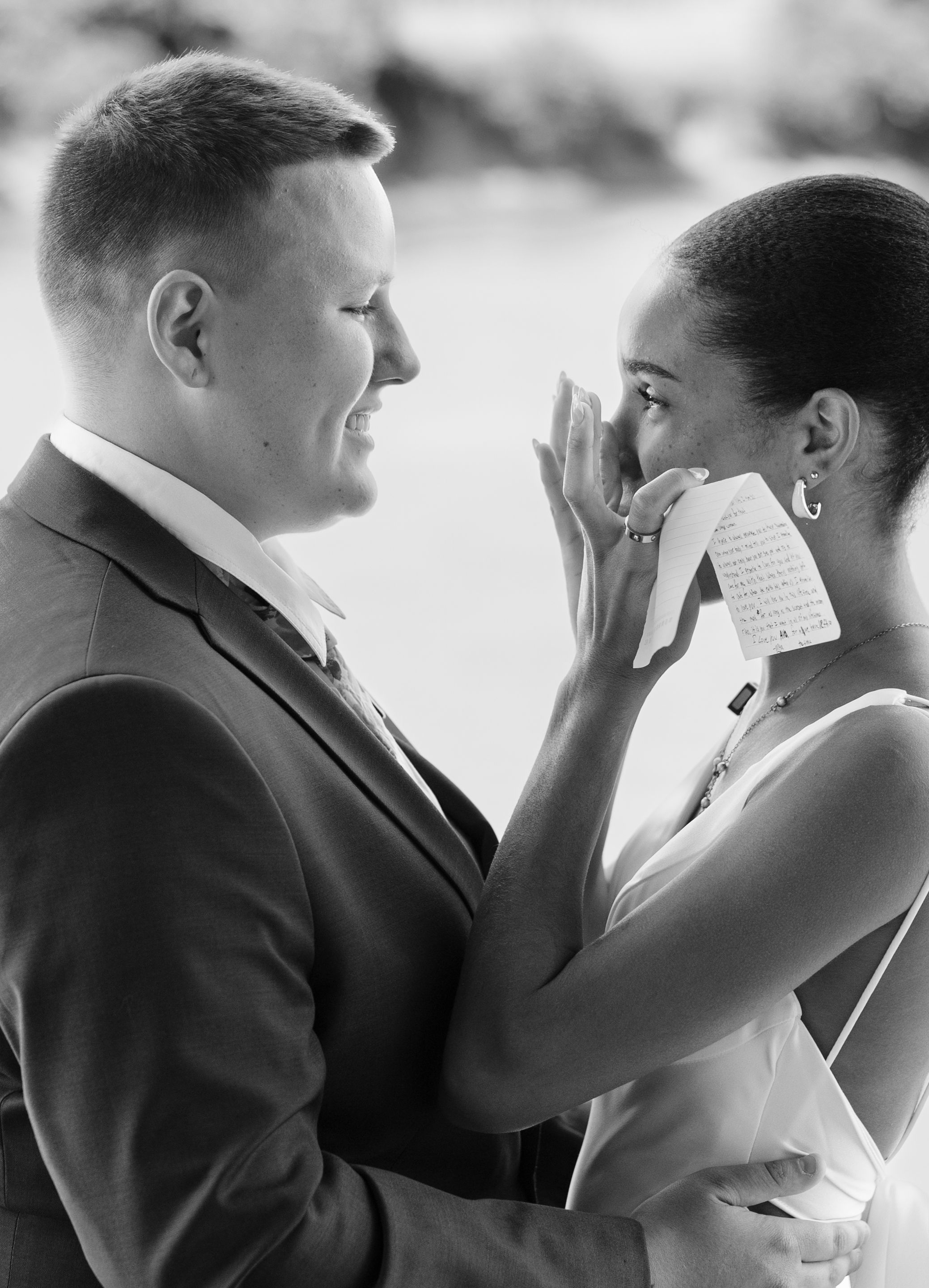 Intimate wedding moment captured under flowing white fabric with delicate floral details.