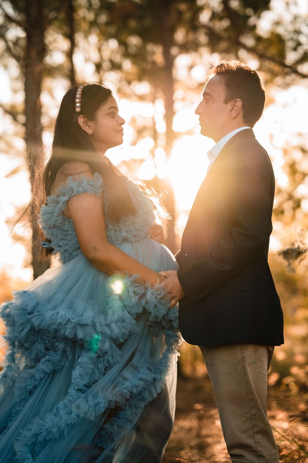 A couple dances in golden sunlight, with a flowing blue tulle dress swirling through the forest.