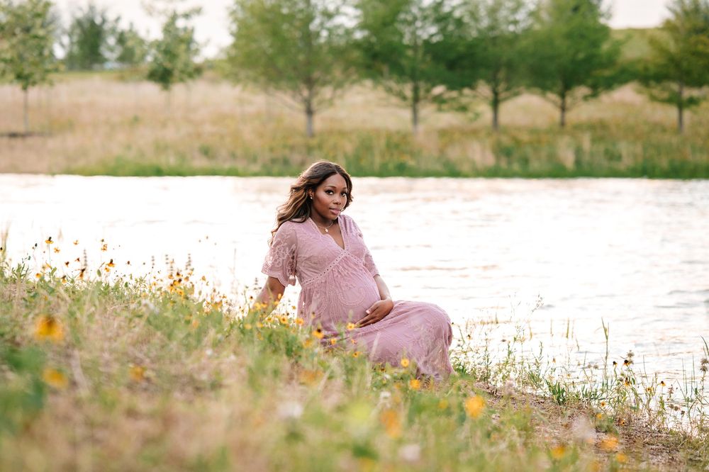 A flowing pink dress stands out against a natural landscape with scattered wildflowers.