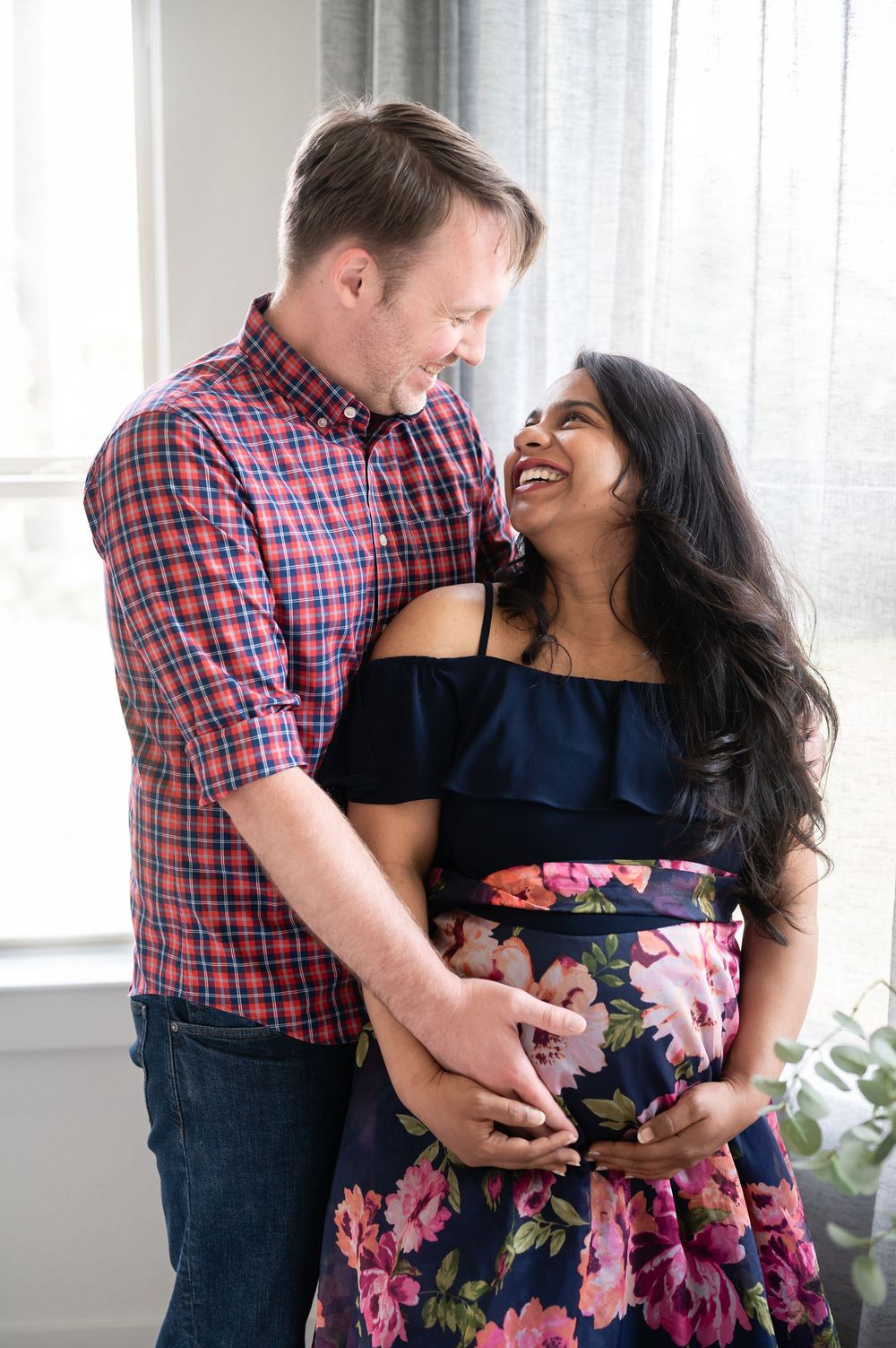 A couple poses together indoors wearing plaid and floral prints.