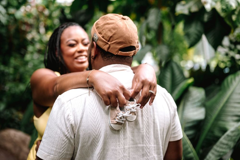 Candid maternity moments captured in white attire against floral garden scenery.