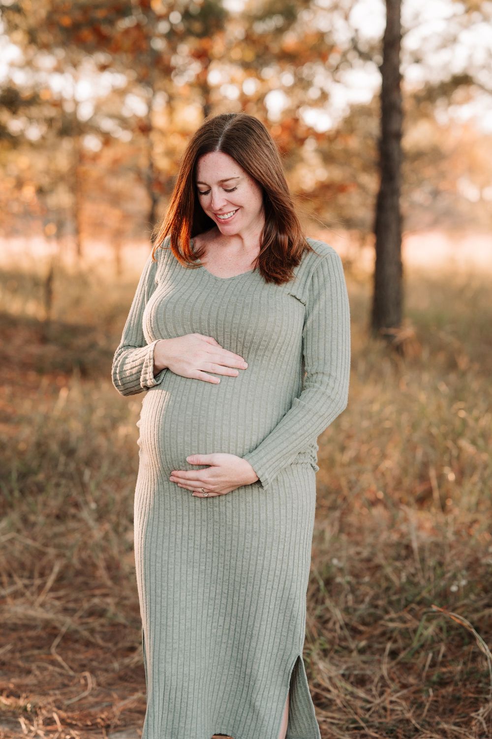 A sage green sweater dress is showcased in an autumn forest setting.