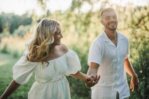 Couple shares intimate joyful moments while sitting together on a picnic blanket outdoors.
