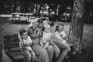Black and white photo of family members sitting together under trees in a park.