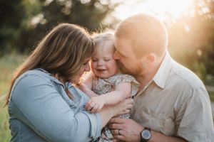 Family shares sweet loving moments together outdoors during sunset photo session.