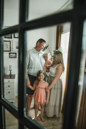 Family portrait viewed through window panes in natural indoor lighting.