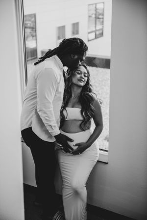 A romantic black and white photo showing a couple by a window.