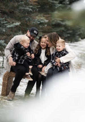 Family of four enjoying outdoor time together by stream in autumn scenery.