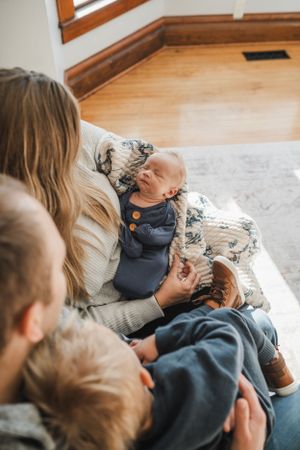 Tender family moment on couch with baby in blue outfit.