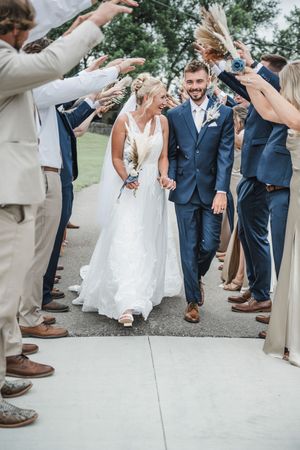 Wedding celebration with guests tossing dried flowers as couple walks through.