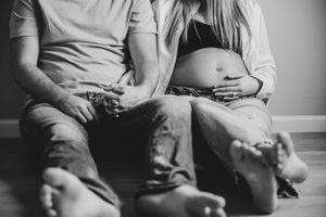 Black and white photo of expectant parents sitting together on floor during maternity session.