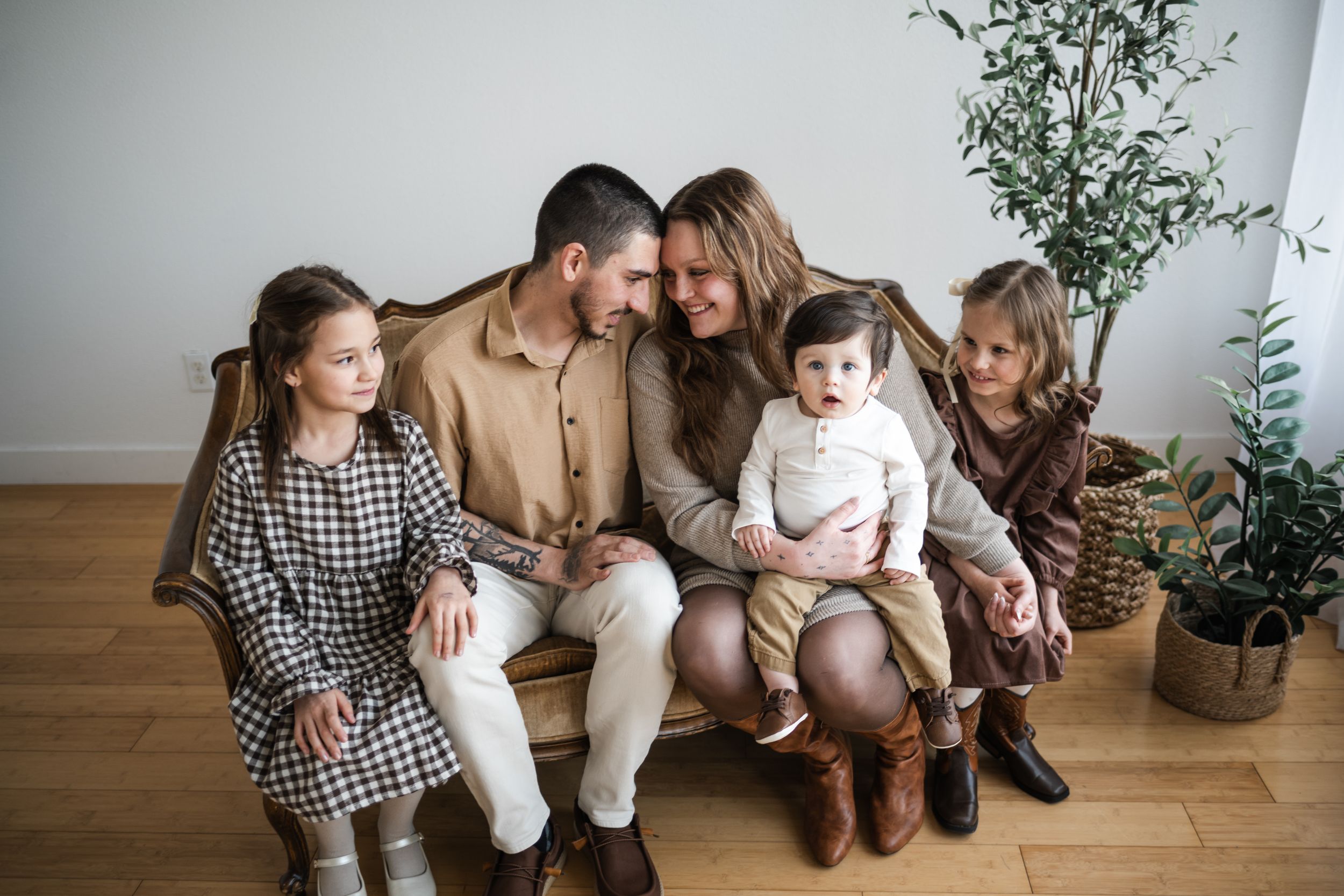 Family sitting together on hardwood floor with indoor plants and natural light creating a cozy home atmosphere.