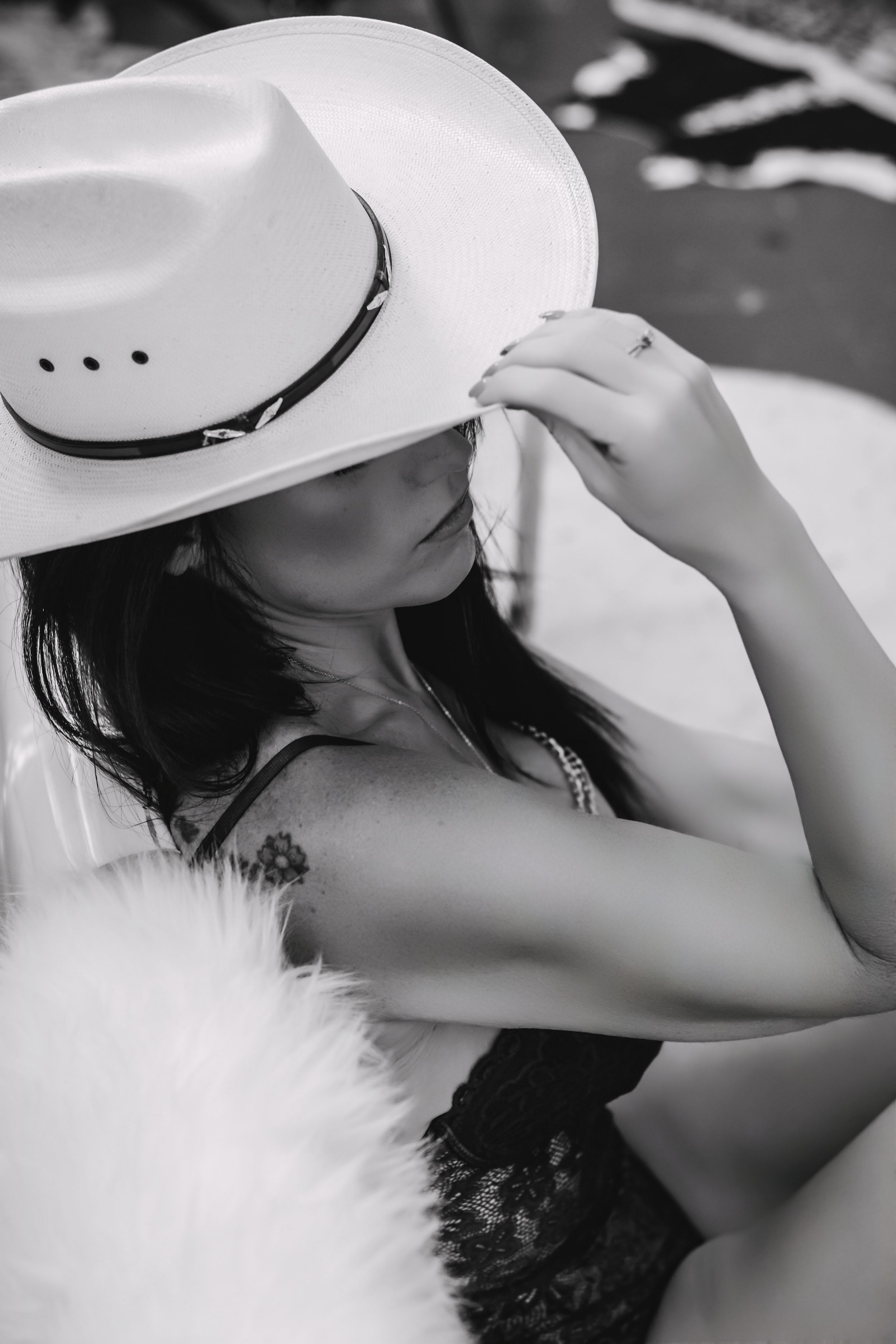 Western boudoir portrait of a confident woman topless with a cowboy hat, showcasing strength and femininity.