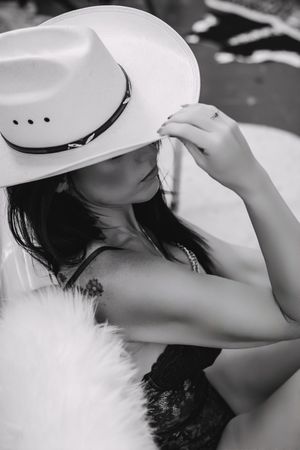 Western boudoir portrait of a confident woman topless with a cowboy hat, showcasing strength and femininity.
