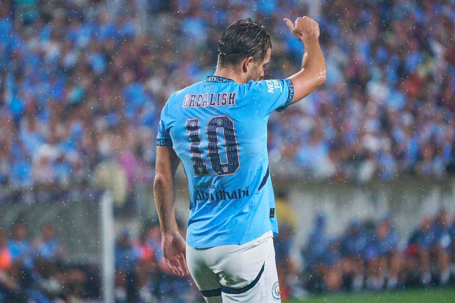 Soccer player in light blue jersey celebrates after scoring during a match with crowd in background.