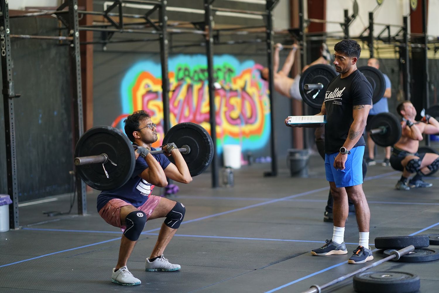 Athletes performing squats during CrossFit training session.