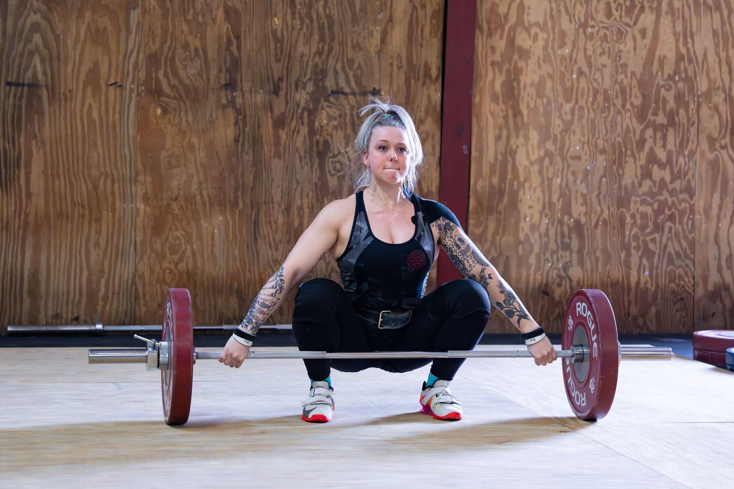 People performing weightlifting exercises with barbells in a gym setting.