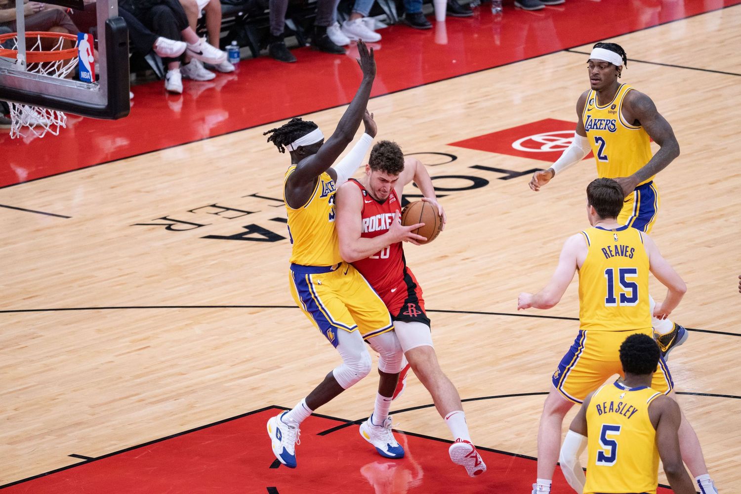 Basketball players compete for possession during an intense game on a wooden court.