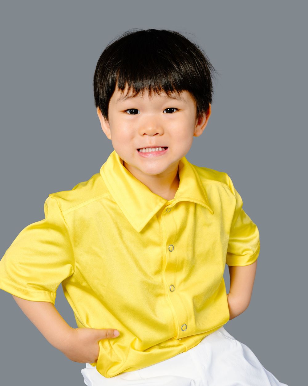 A sequence of four photos showing someone in a bright yellow shirt making playful expressions against a gray background.