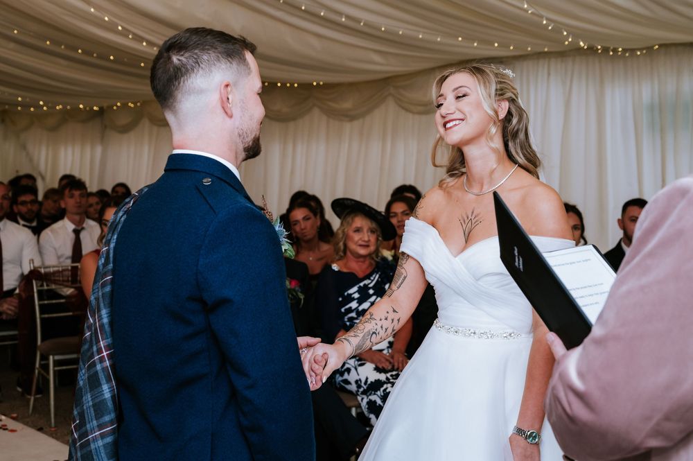 A couple dances together at their wedding reception in a decorated marquee tent with fairy lights.