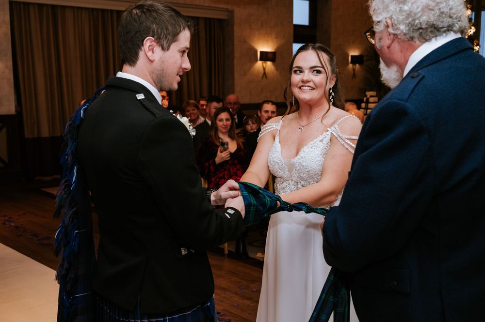 A couple shares an intimate dance moment on a wooden floor during a wedding reception.