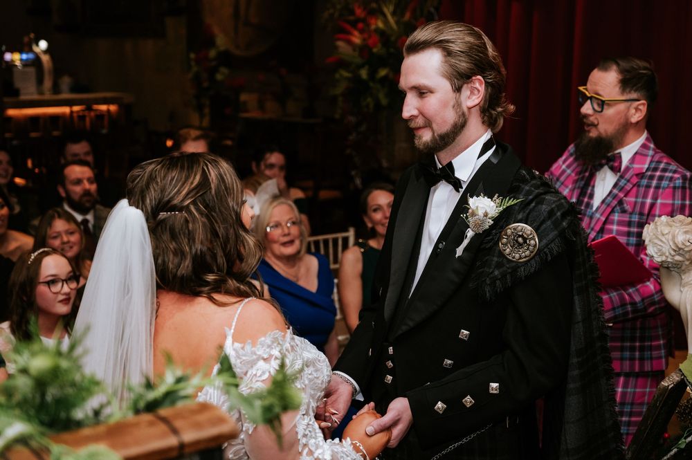A couple shares a joyful moment during their traditional Scottish wedding celebration.