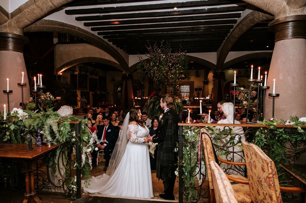 Elegant wedding reception venue with rustic wooden beams and romantic candlelit table settings.