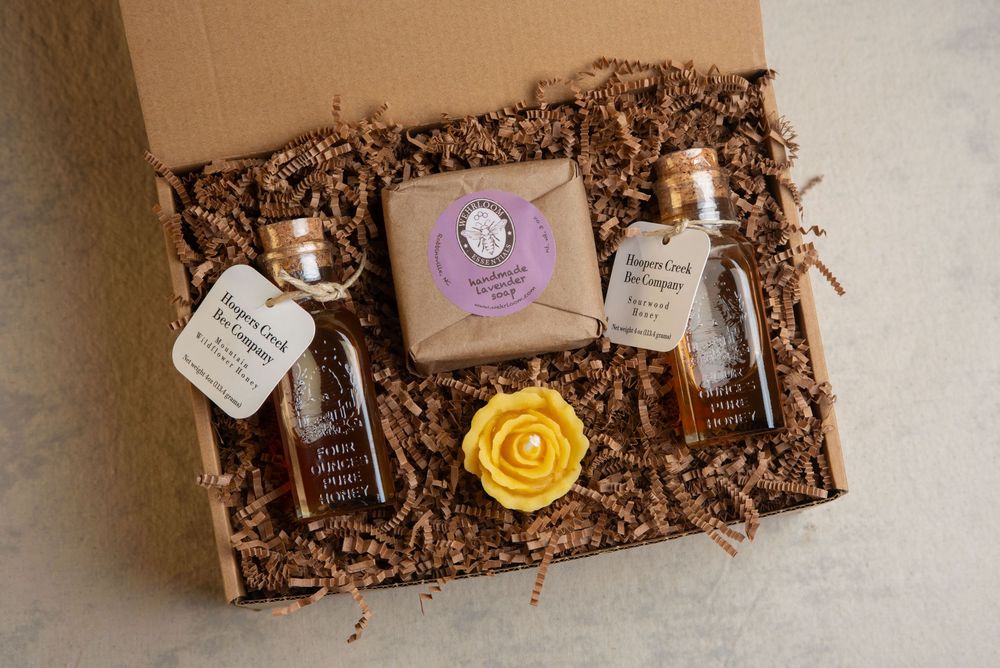 Memphis product photography studio shot of an open gift box of bottles of honey, and beeswax soap and candle.