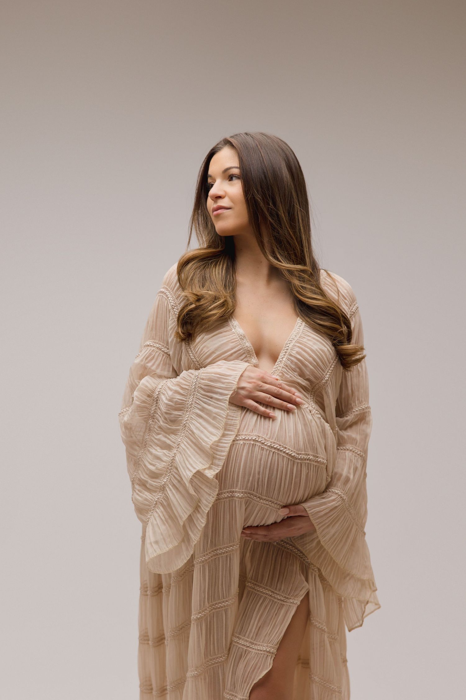 Woman in sheer textured gown with deep neck line and large billowing sleeves