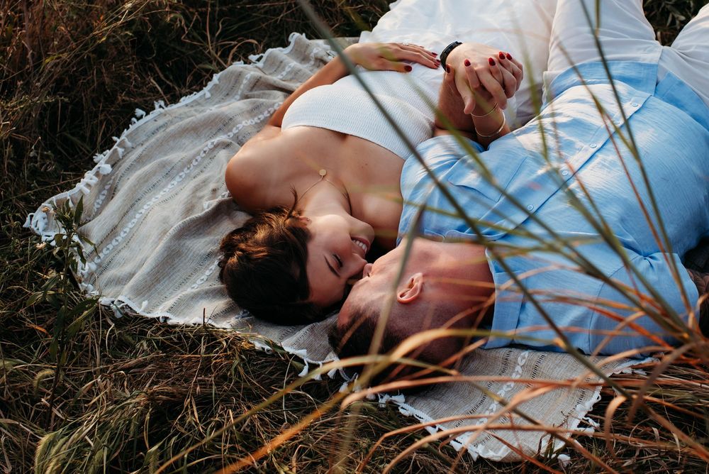 A person in white dress lies on dried twigs creating artistic moody portraits in a rustic outdoor setting.