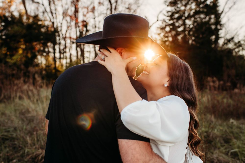 A couple shares an intimate moment at golden hour while wearing western-inspired attire.
