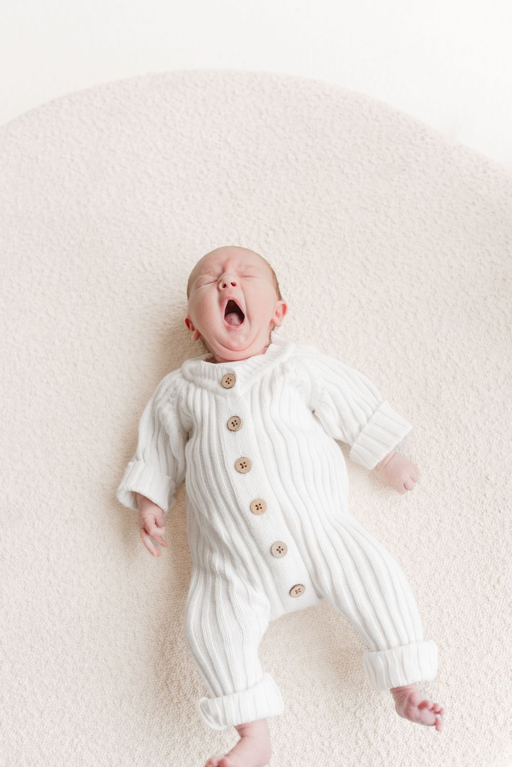 Baby yawning wearing a neutral romper at a Toronto Newborn Photoshoot captured by Jess GC Photography