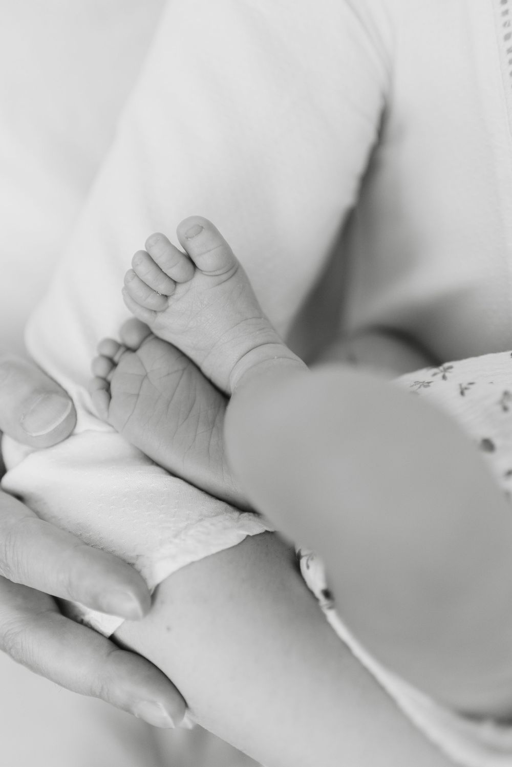 Close up in black and white of baby's feet while in parent's arms, taken at a newborn photoshoot captured by toronto newborn photographer