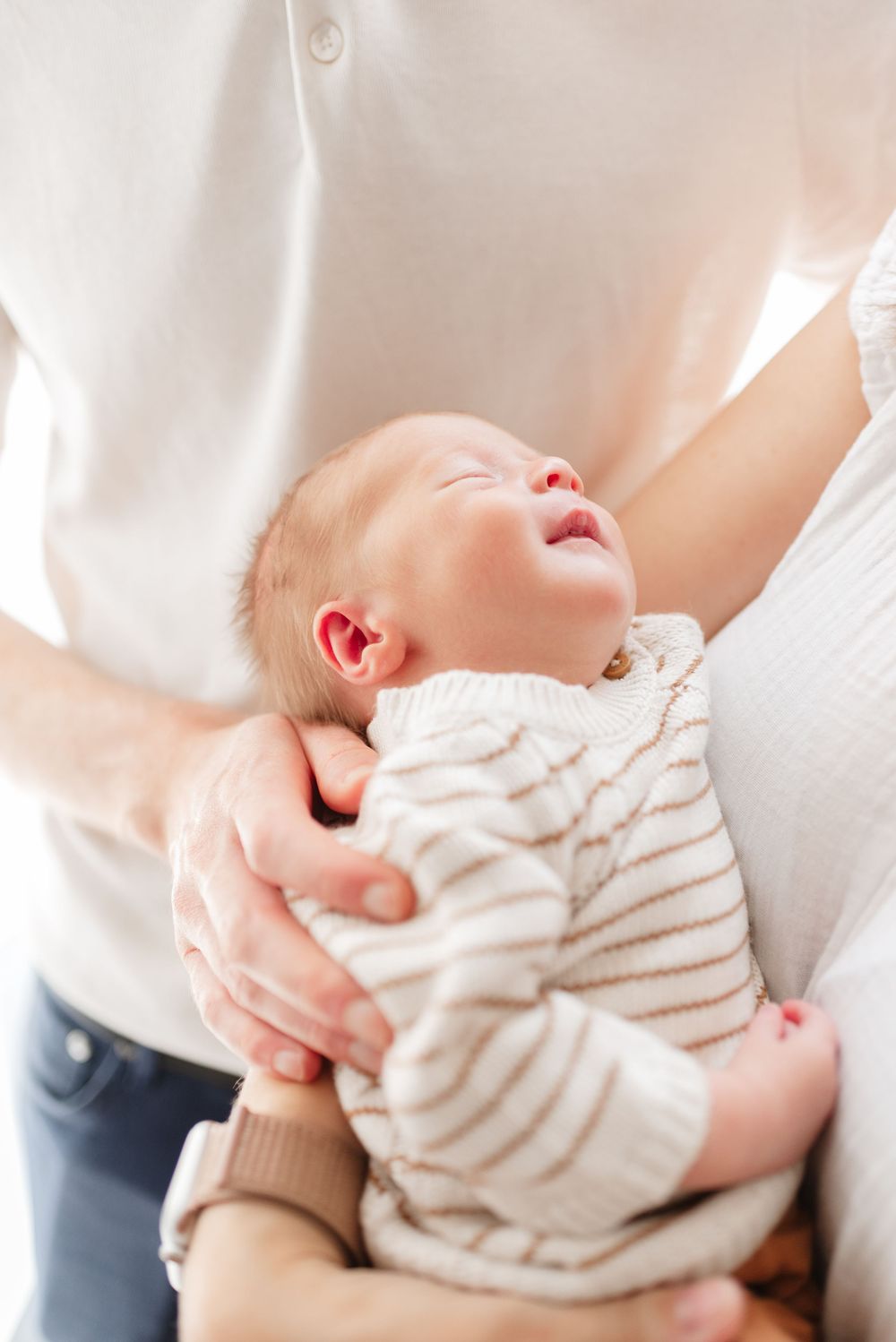 Newborn baby smiling while at mom's lap at Toronto home newborn photography session.