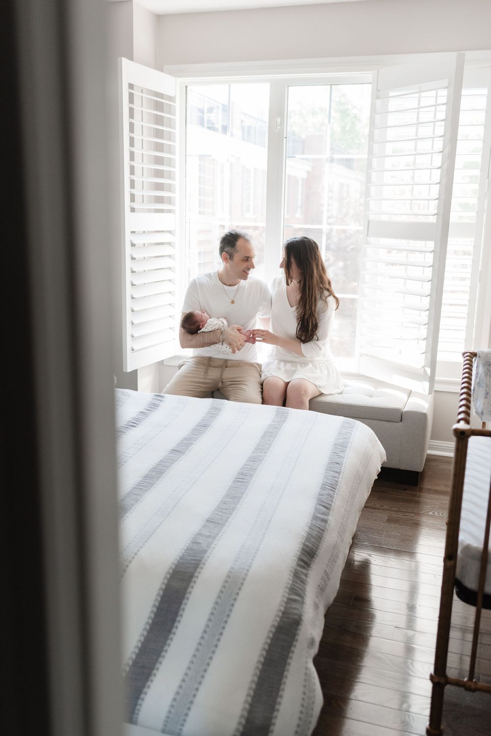 Parents looking at each other while holding newborn baby in Toronto home, natural newborn photography
