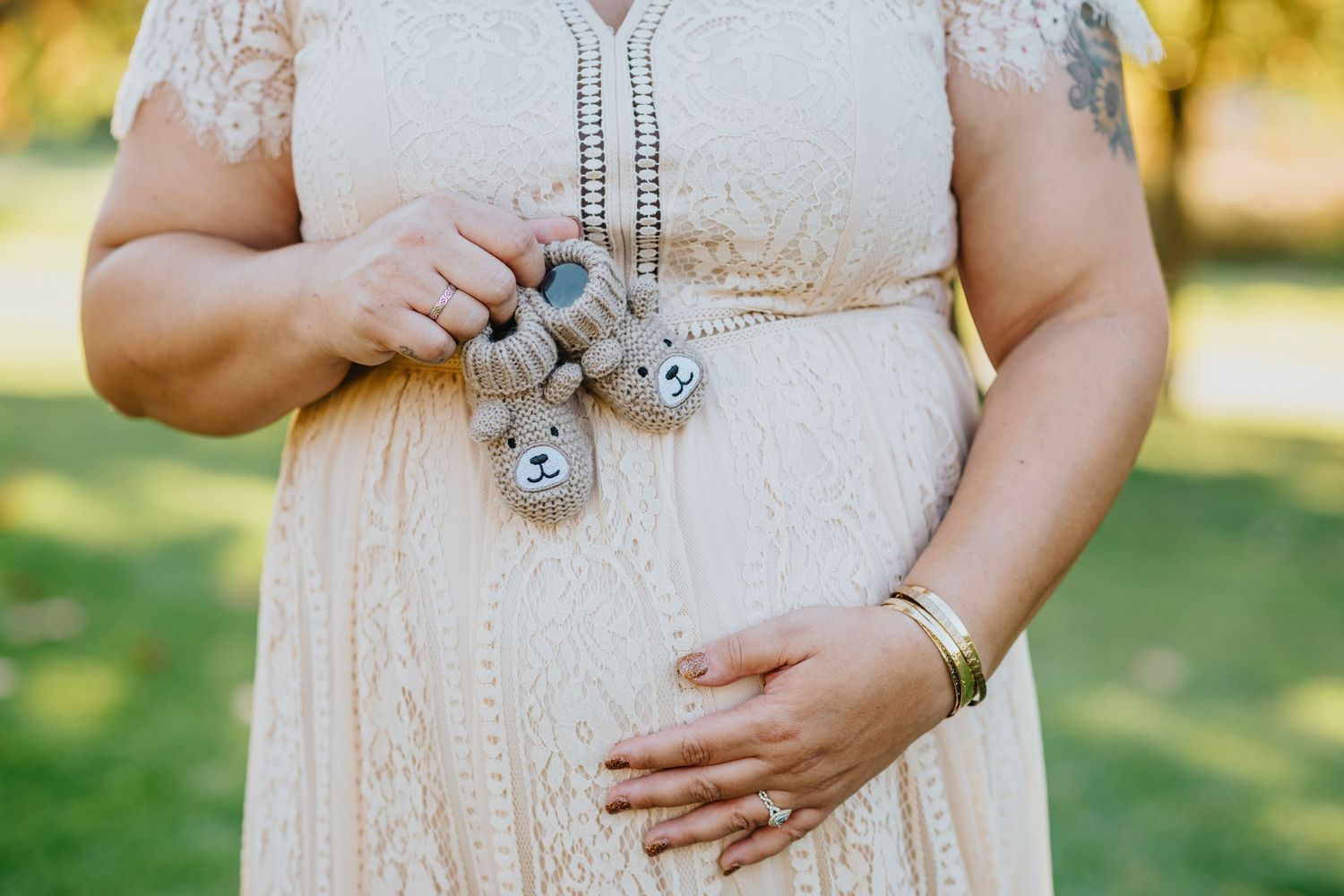 Close up of expectant mother's hands holding tiny baby shoes and cradling baby bump.