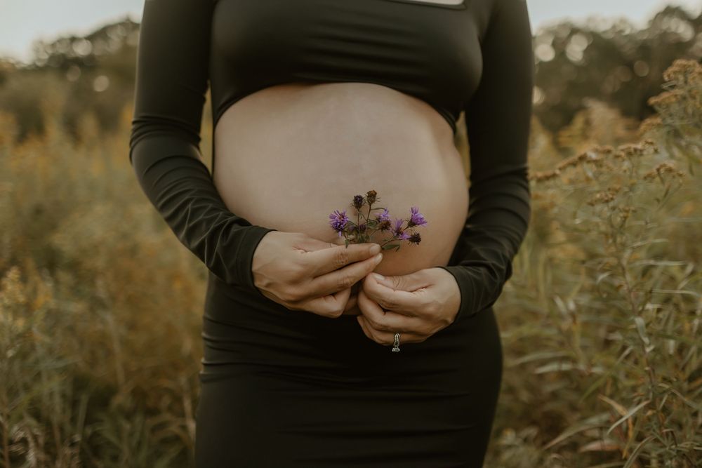 Close-up shots of pregnant belly with hands tenderly placed during outdoor maternity session.