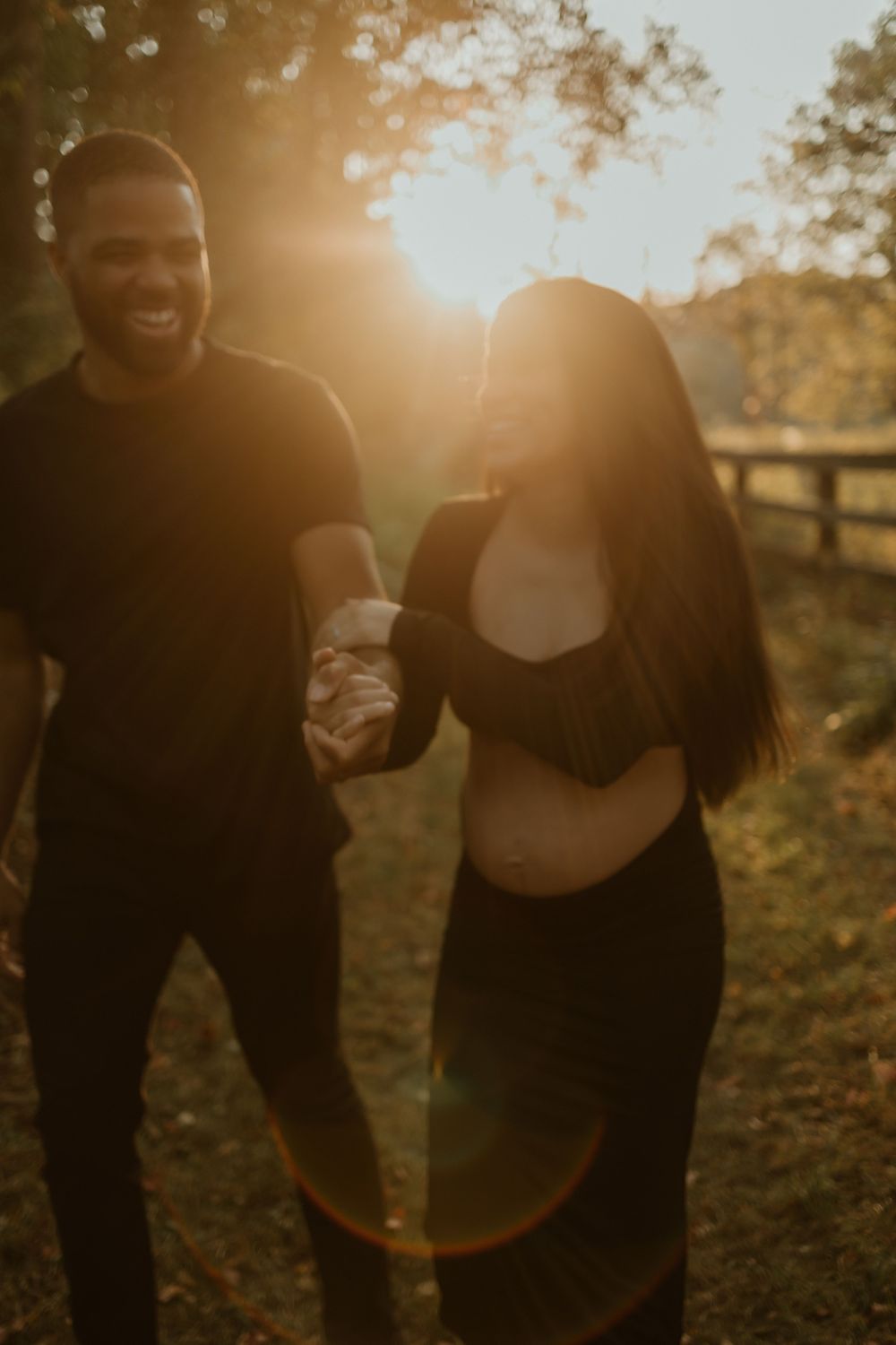 A couple shares a tender moment in a sunlit field during golden hour.