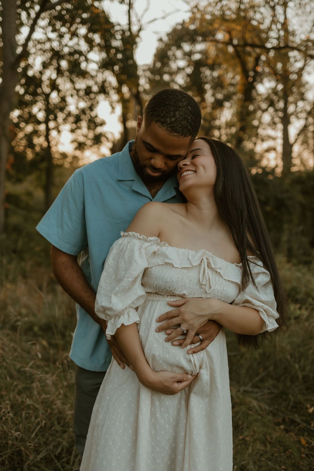 Maternity session featuring couple in white dress and blue shirt sharing intimate moments in nature.