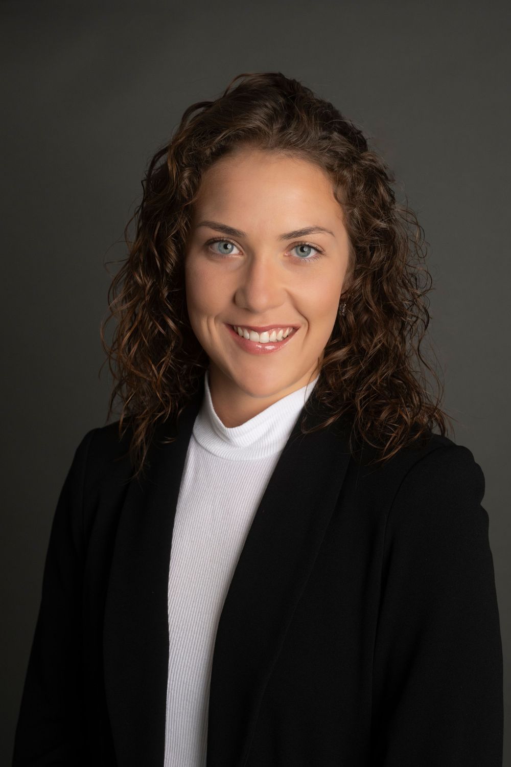 Professional studio portrait series showing a figure in black blazer and white turtleneck against dark background.