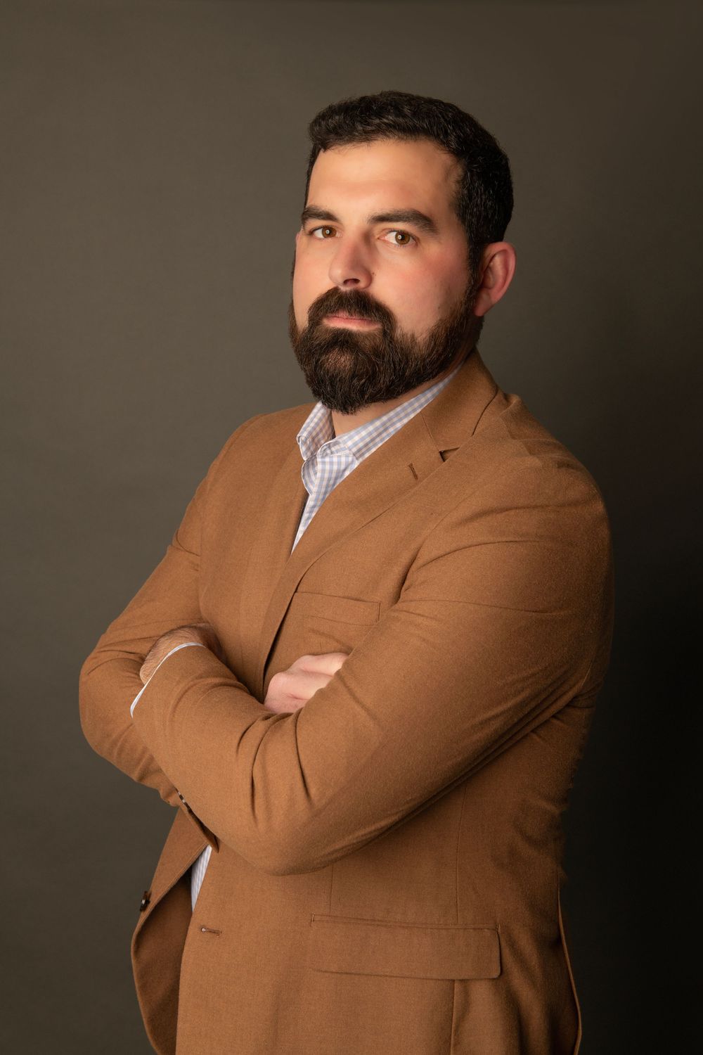 Professional portrait series showing person in brown blazer and checkered shirt against dark background in different poses.