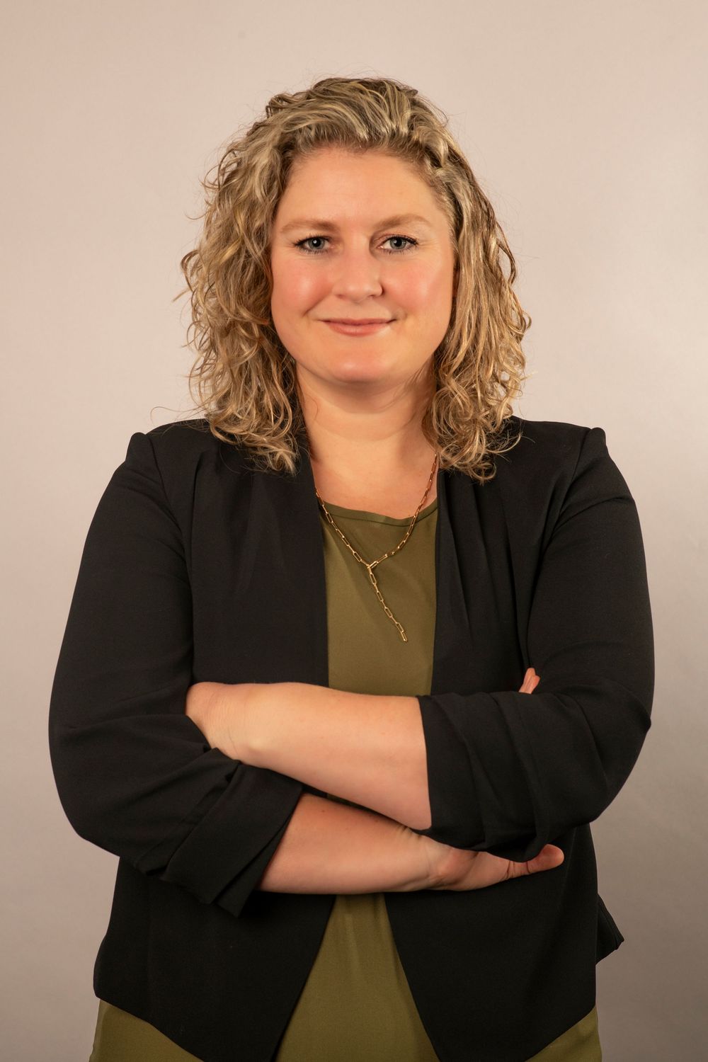 Professional headshot series showing confident poses in a black blazer and olive top against neutral background.