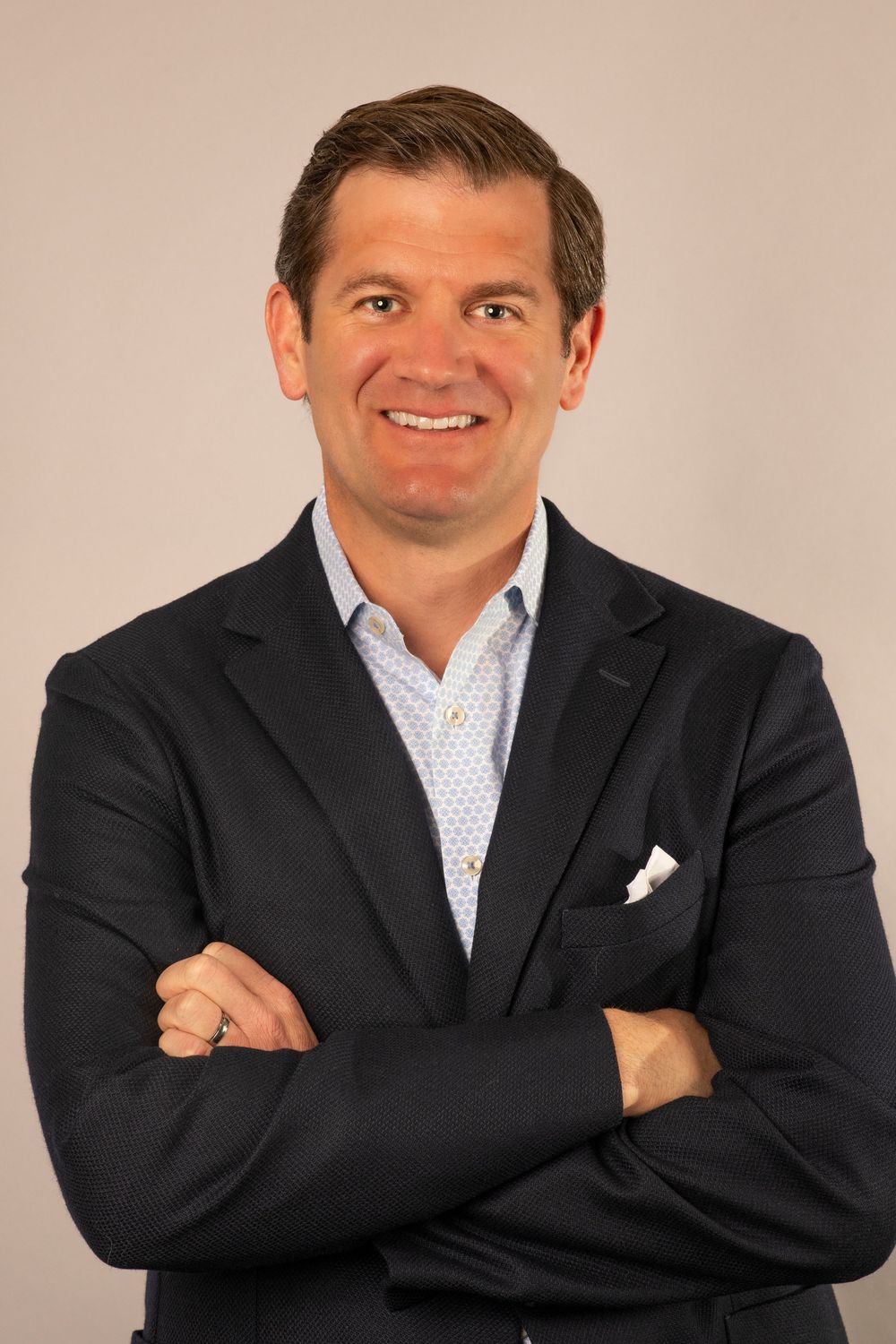 Professional headshot series showing person in dark suit and white patterned shirt with crossed arms in various poses.