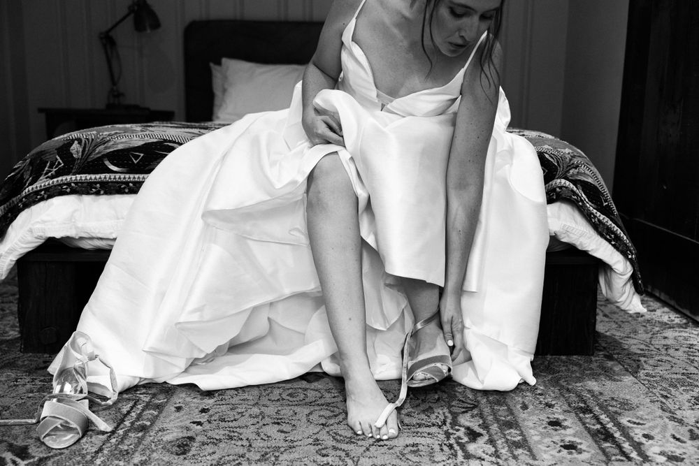 Black and white image of a bride putting on her shoes in the bridal suit at The Mad River Barn in Waitsfield, VT