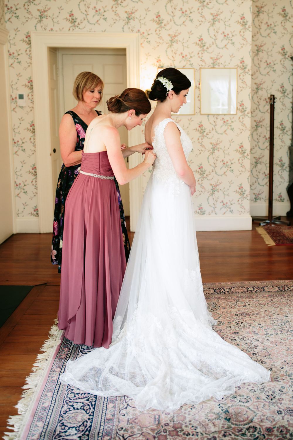 Briade getting into her dress in the bridal suit at the historic Lyman Estate and Greenhouses in Waltham, MA