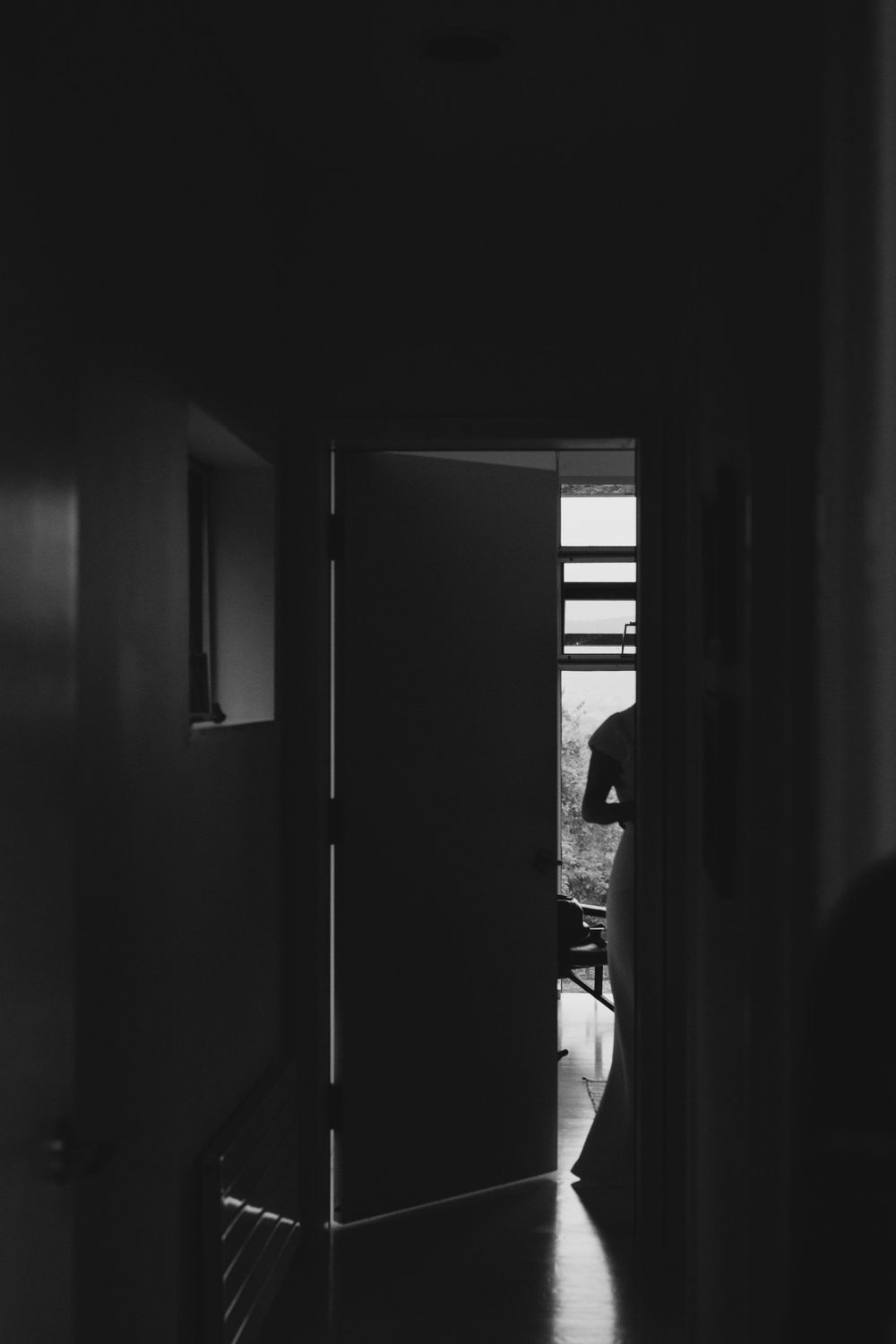 Silhouette of a bride getting ready captured through a crack in the door on her wedding day